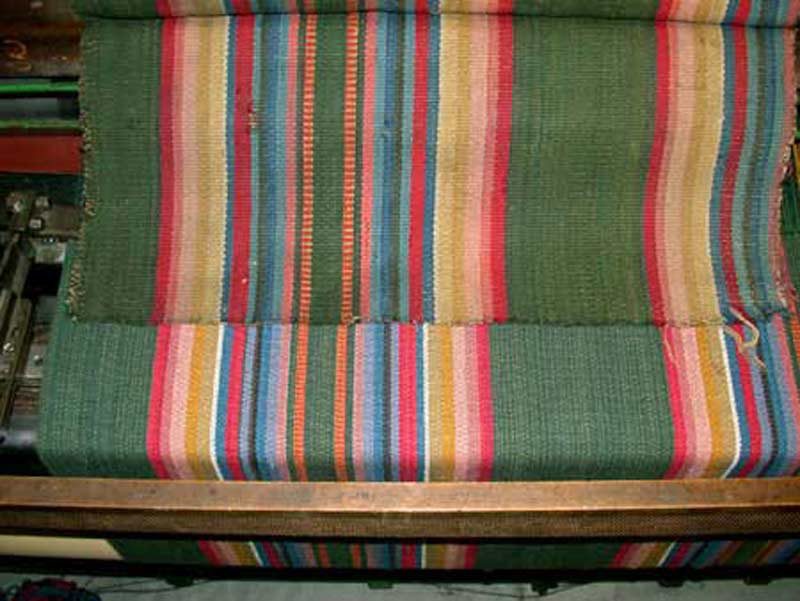 We can produce very close reproductions of historic carpet. This image shows a surviving original fragment (above) and our reproduction (below) as it is being woven on the loom. We custom dyed the yarns and matched the pattern exactly.